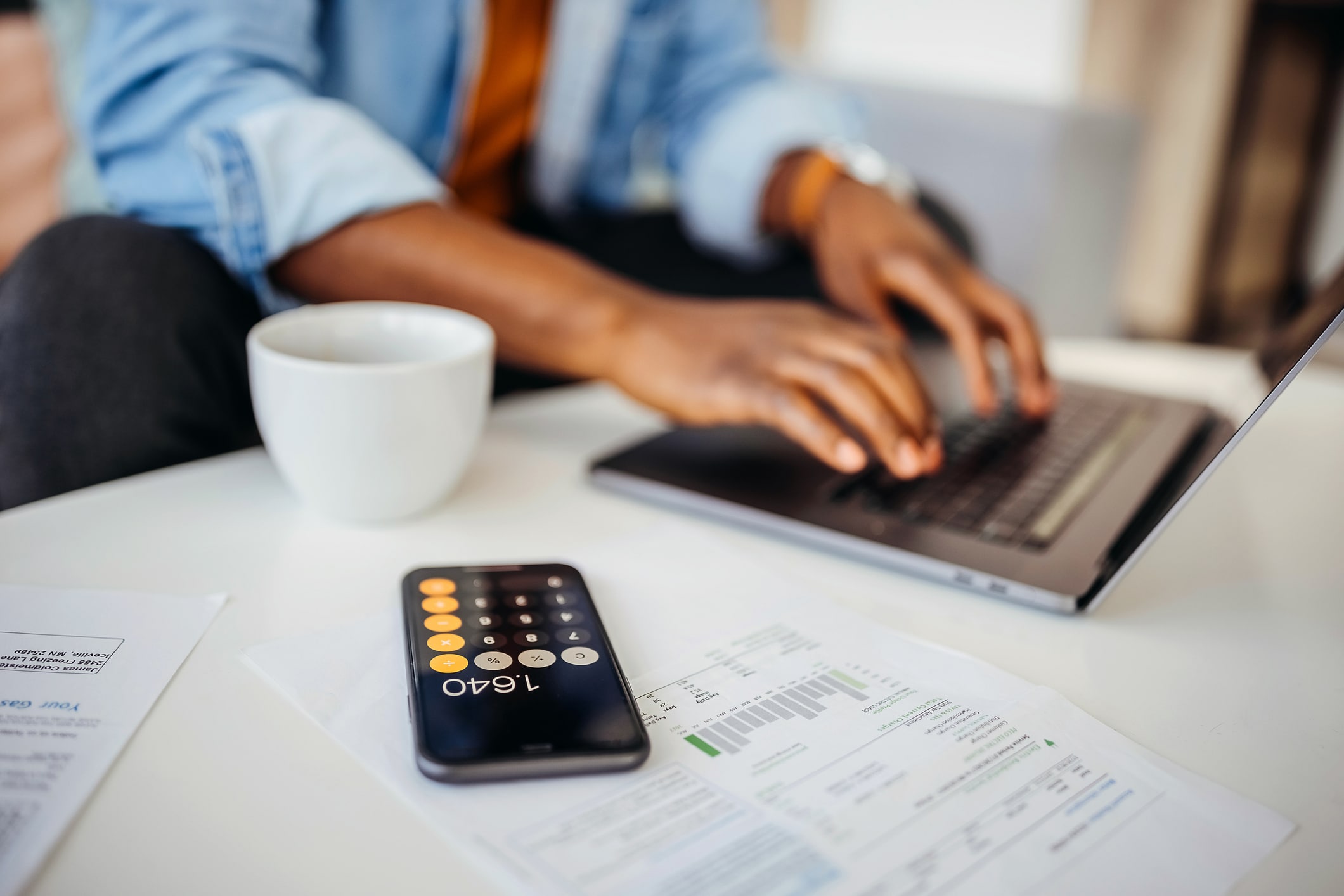 A close-up photo of a calculator next to a printed 401(k) contribution worksheet and a pen on a home office desk