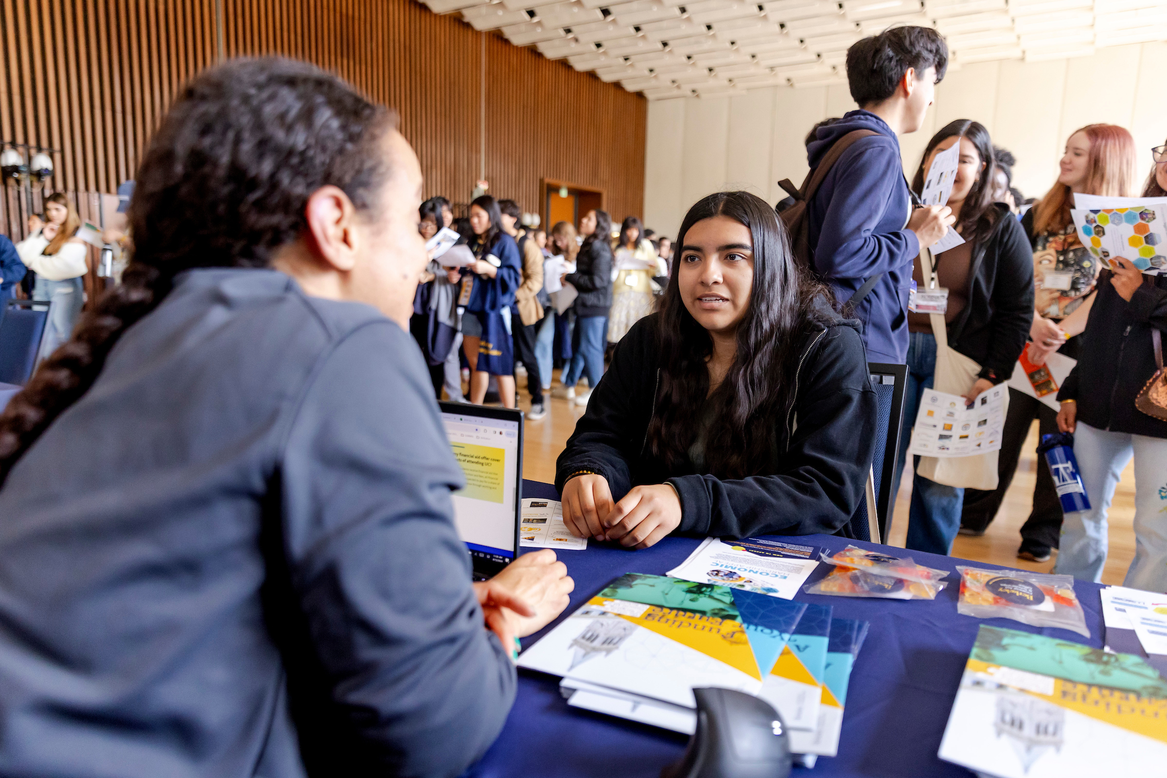 A college student sitting across from a financial aid counselor in an office, reviewing paperwork together, realistic photo