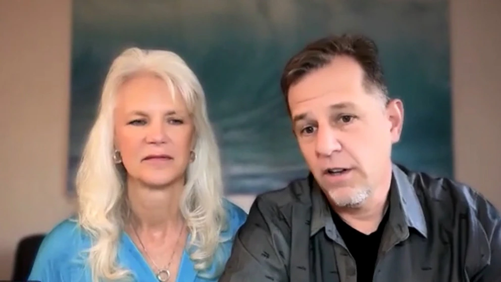 A couple seated across from a mortgage lender at a desk in a bright office, reviewing documents together, candid realistic photo