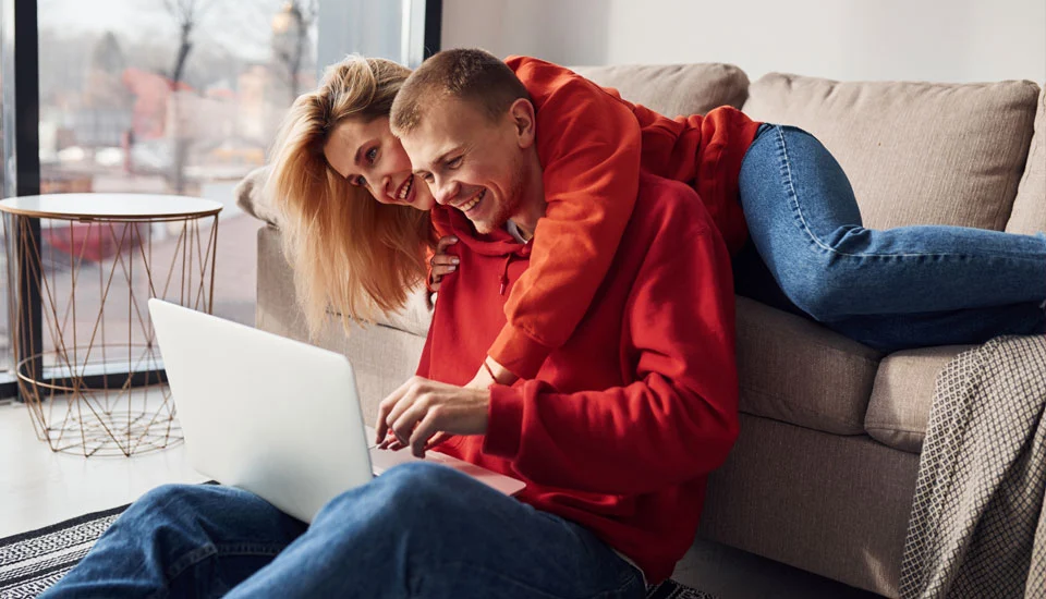 A couple sitting on a couch reviewing a credit report on a tablet together, focused expressions, evening indoor lighting, realistic photo