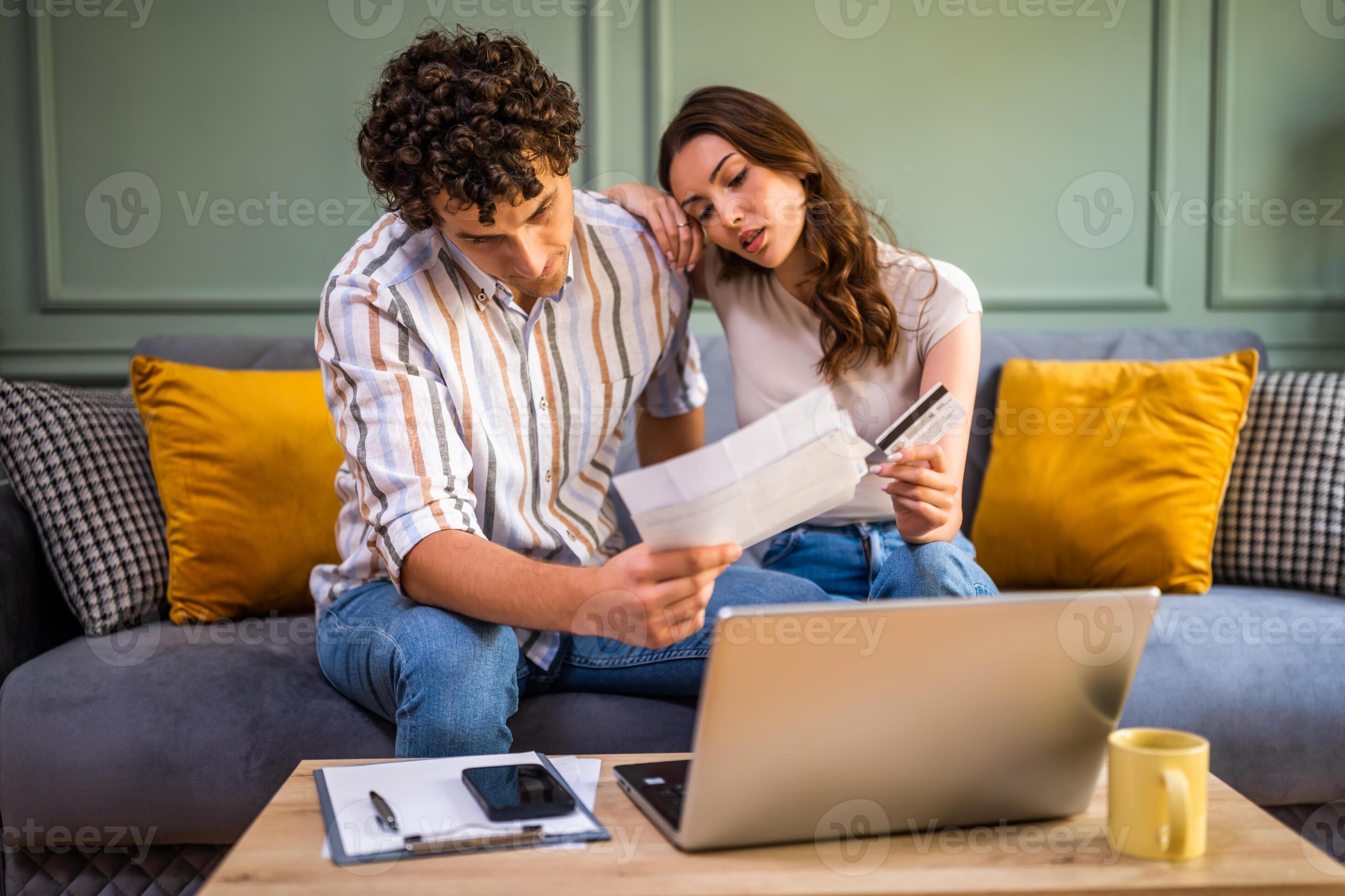 A couple sitting on a couch reviewing home budget documents and a laptop in a living room, realistic photo