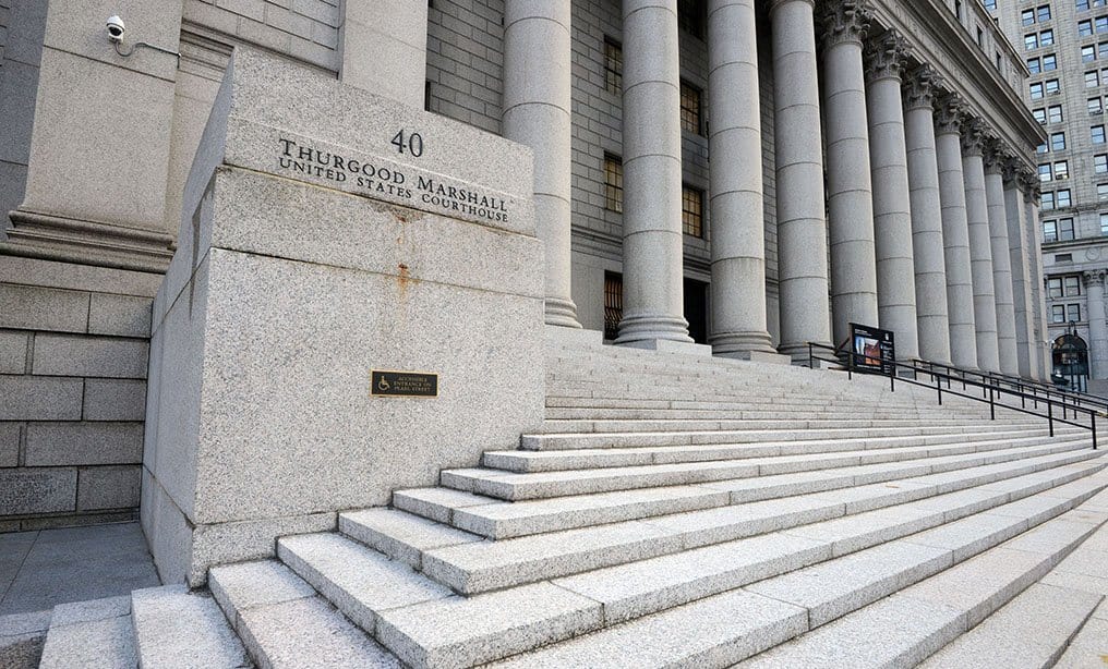 A courthouse entrance with stone steps and a U.S. flag outside, representing the legal fight over PSLF rules