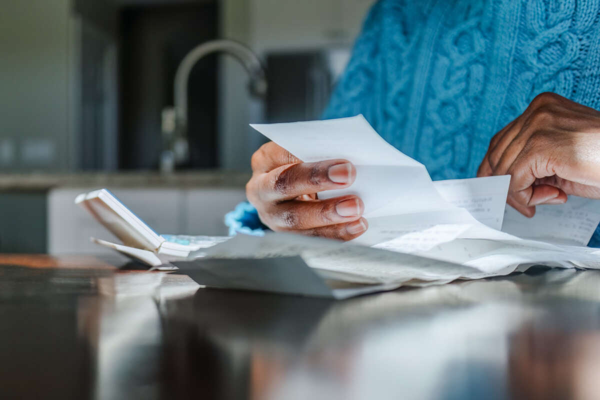 A federal student loan borrower sitting at a kitchen table reviewing printed loan documents and a laptop open to a student aid website, natural window light, realistic photo