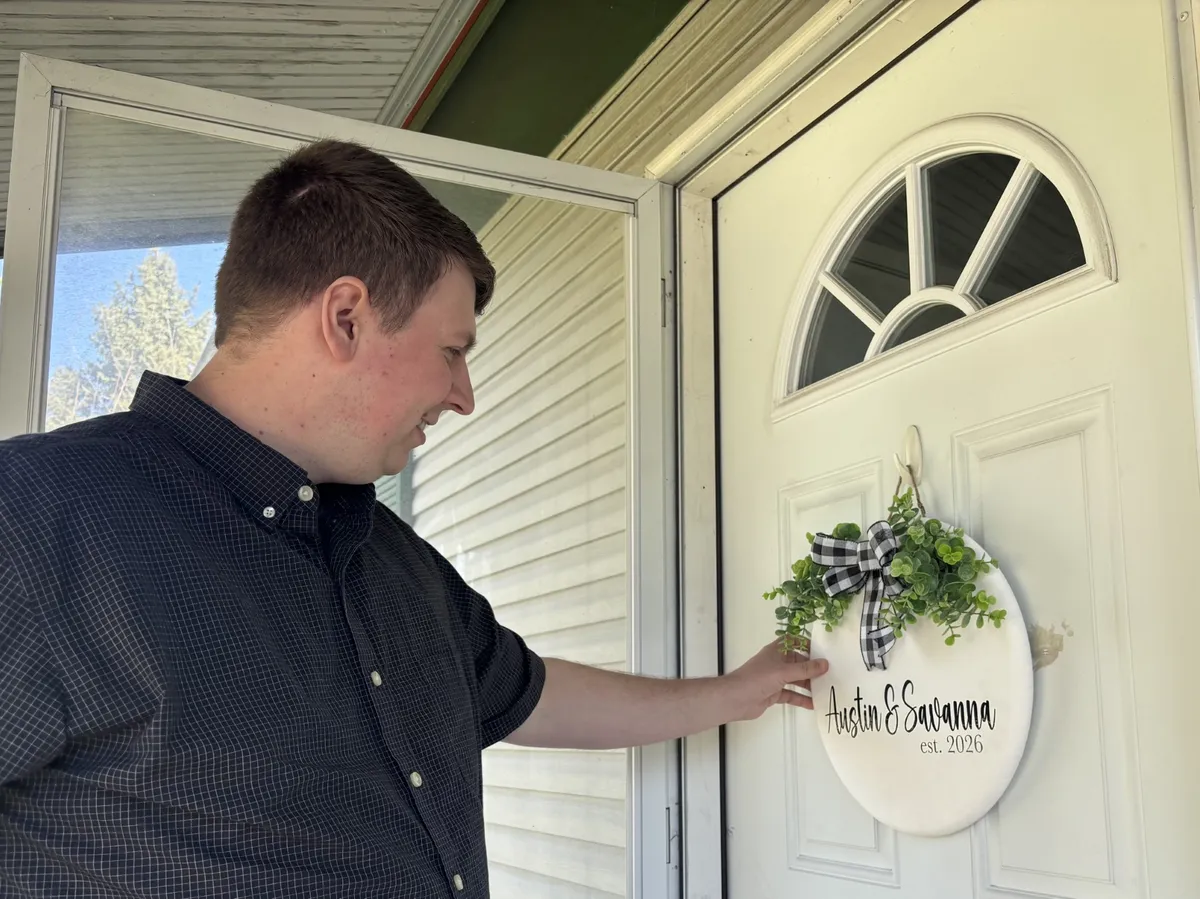 A first-time homebuyer sitting at a kitchen table signing mortgage paperwork with a real estate agent nearby in a Columbus, Ohio home, candid photo