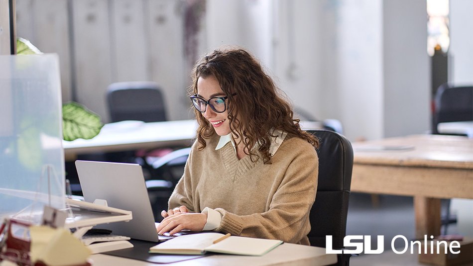 A mid-career employee sitting at a kitchen table with a laptop open to a benefits portal, reviewing student loan repayment benefit options next to a notebook and a coffee mug, realistic photography style