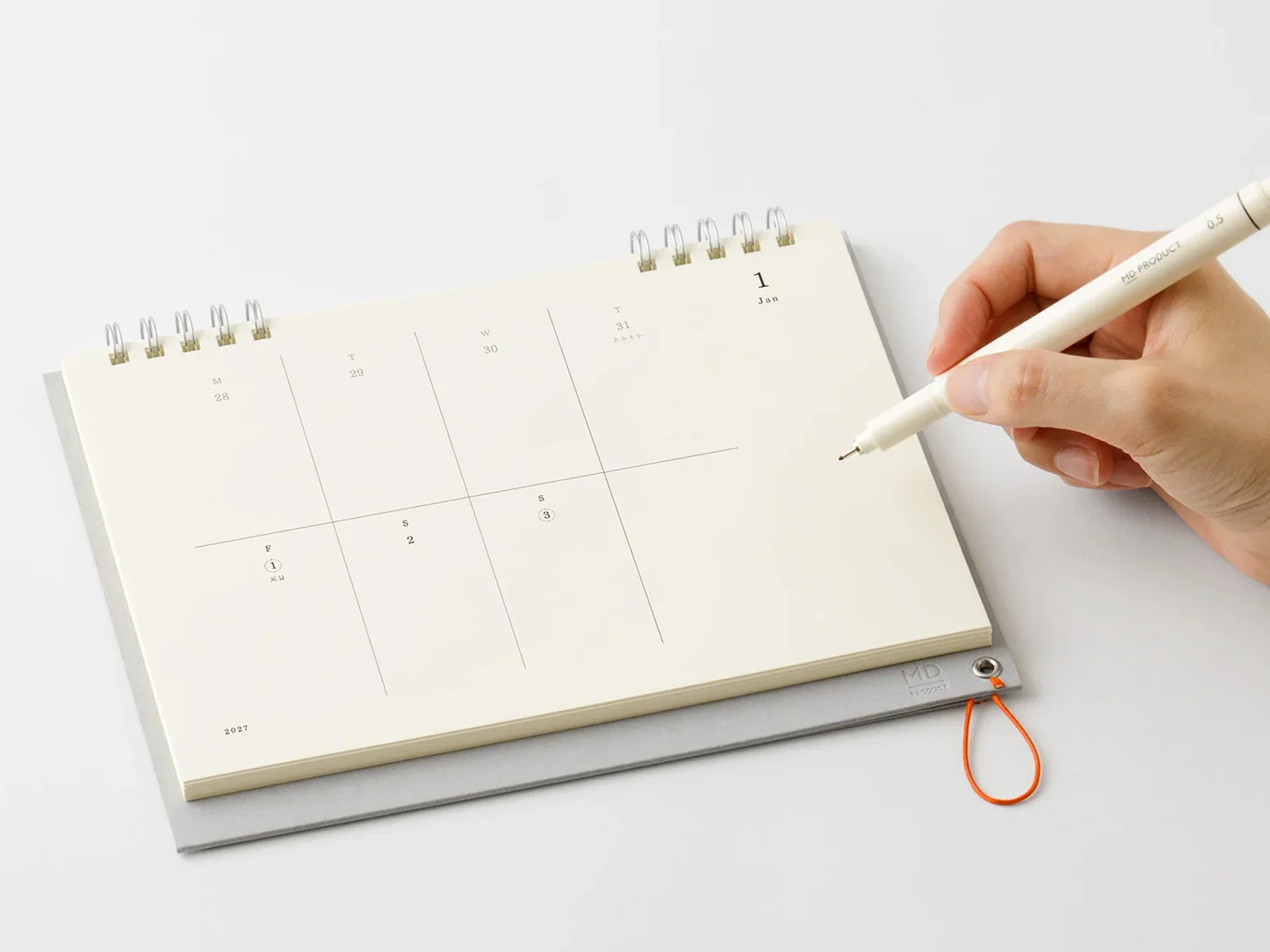 A paper calendar opened on a desk with a pen resting on it, suggesting someone is counting down to an enrollment deadline