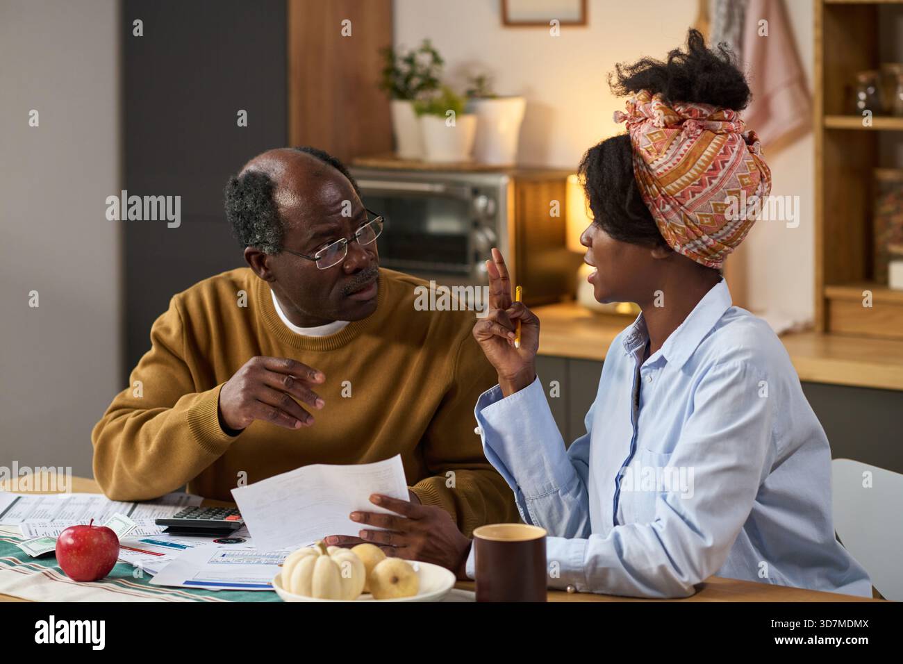 A person at a dining table sorting tax forms and a 401(k) distribution letter next to a calculator, realistic home photo