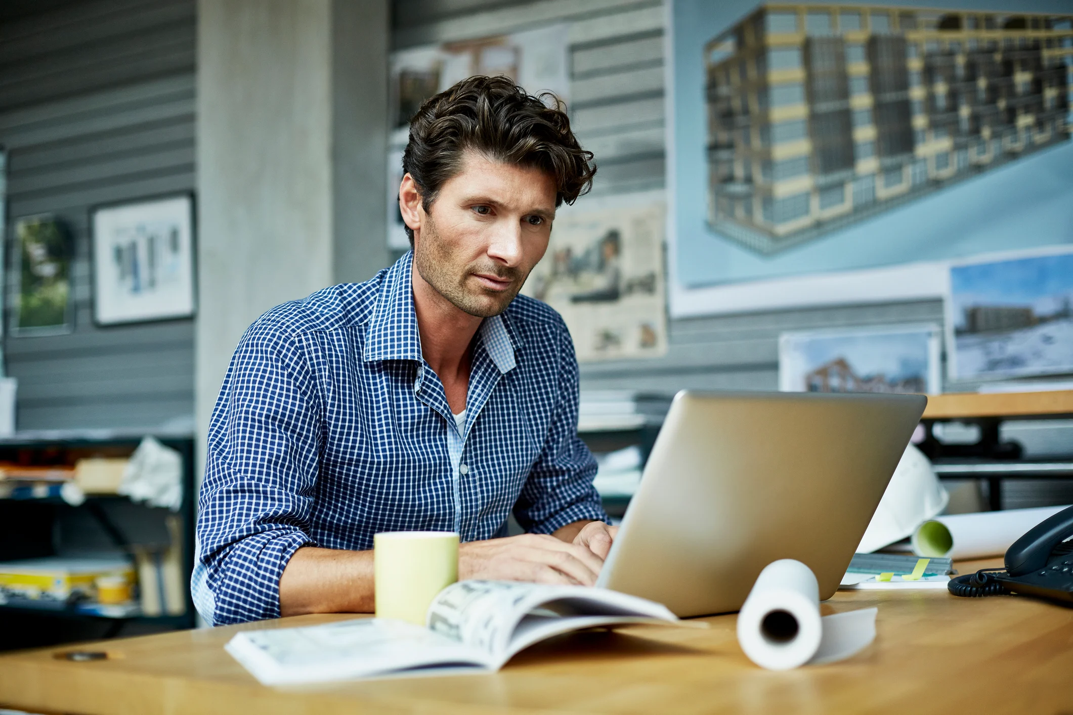 A person filling out 401(k) contribution election paperwork on a desk with a laptop and a cup of coffee, realistic office photo