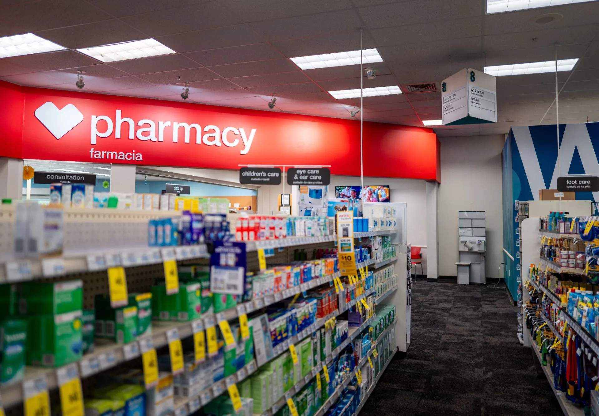 A person holding a prescription bag and a credit card while standing at a pharmacy checkout counter, realistic indoor photo