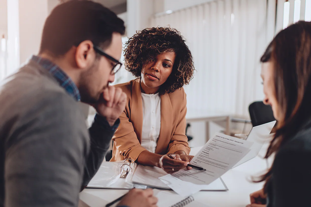 A person meeting with a financial advisor at a small office table, reviewing retirement account documents together, natural professional photo
