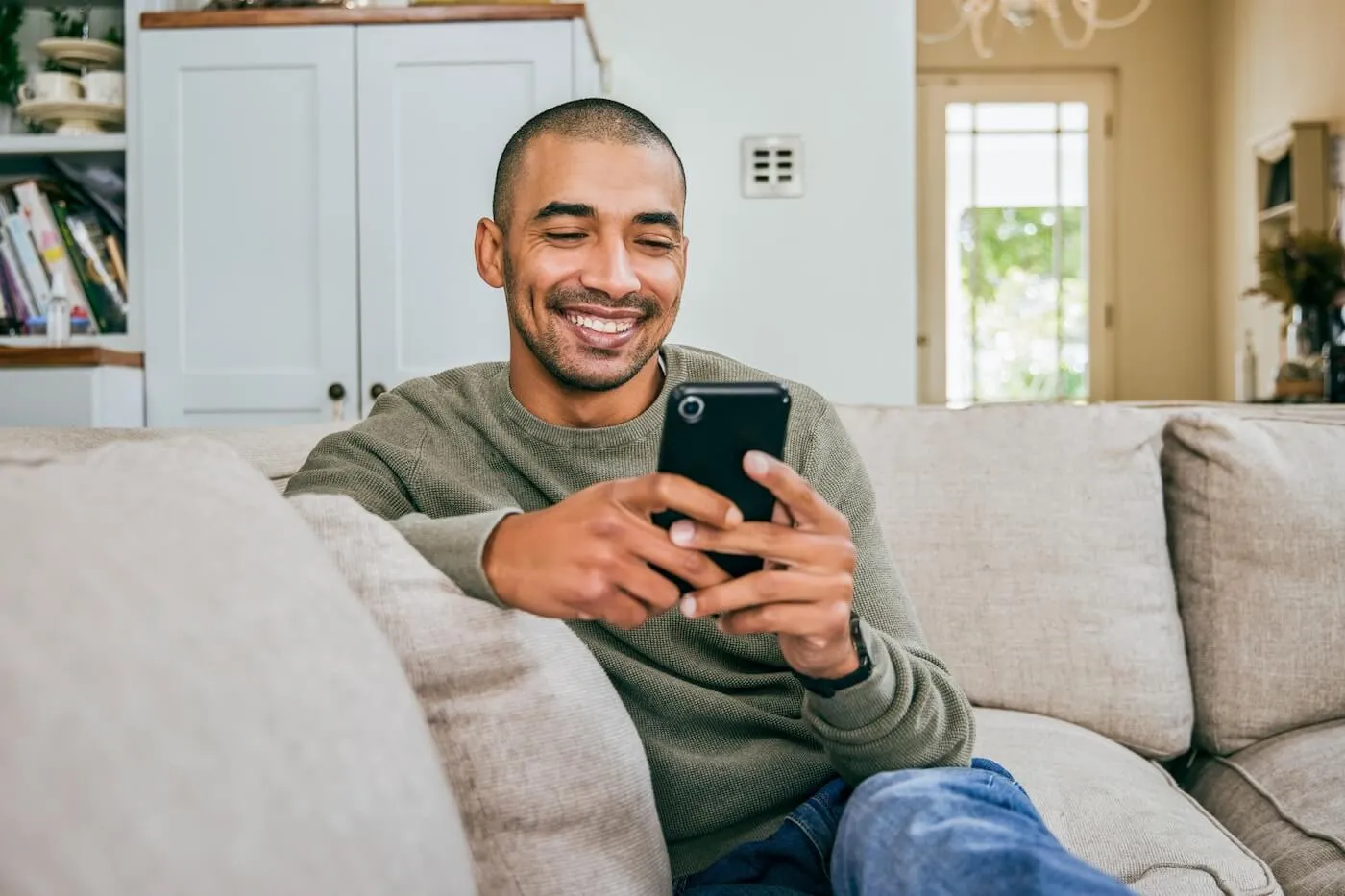 A person sitting on a couch making a phone call while looking at a monthly budget on a laptop, realistic photography style