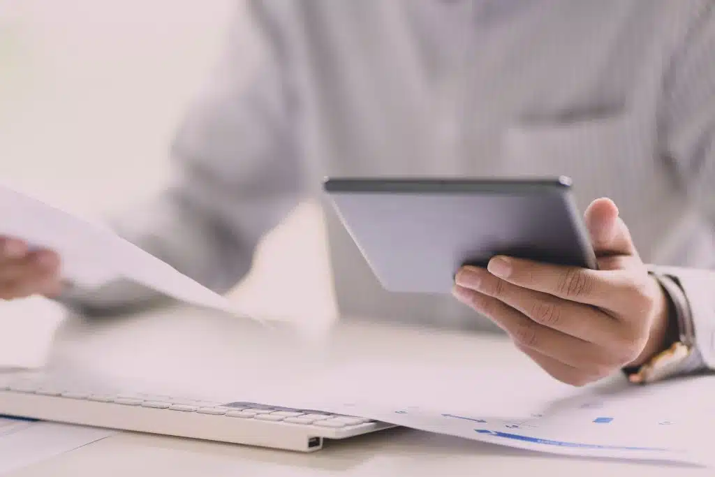 A real-life photo of a person at home using a laptop at a dining table, representing comparing loan offers and credit inquiries