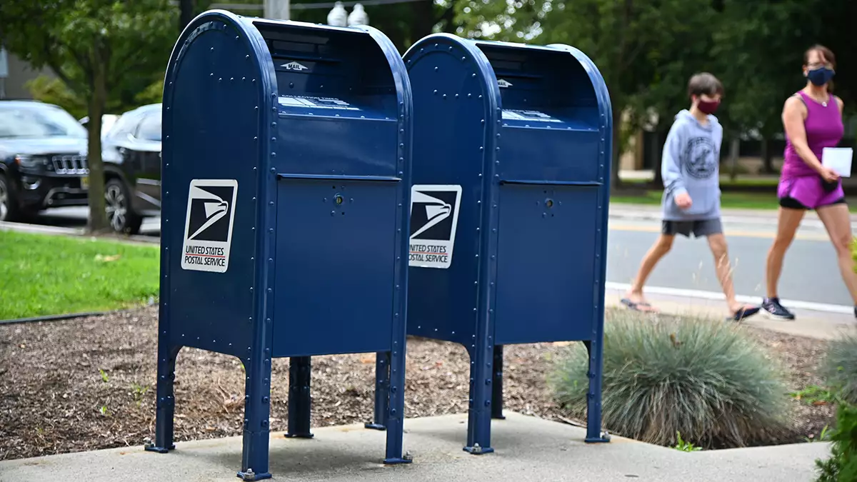 A real-life photo of a person placing an envelope into a blue mailbox on a residential street, representing mailing a credit dispute letter