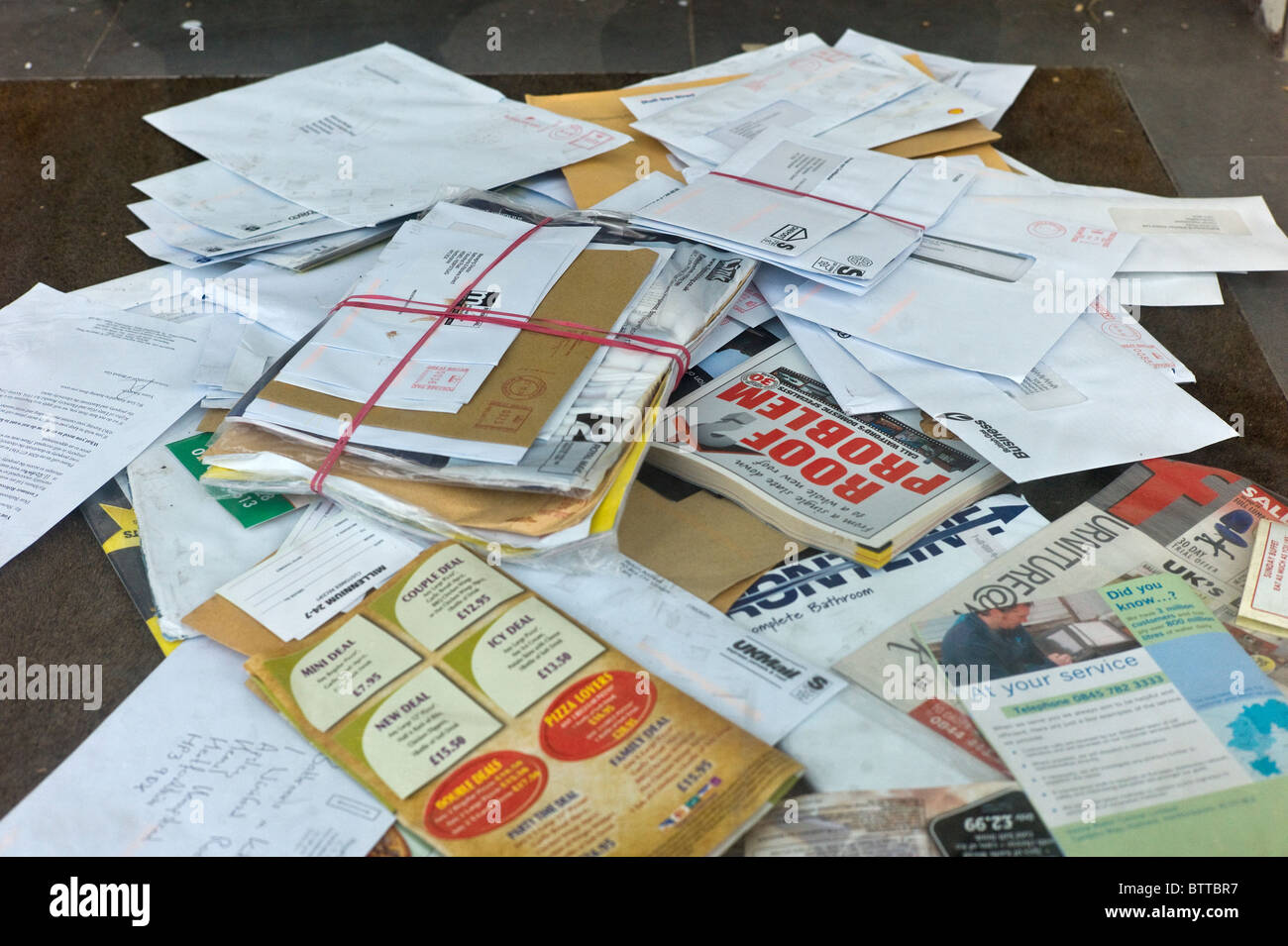 A real-life photo of a stack of unopened mail on an entryway table in a home, representing bills and potential collection notices
