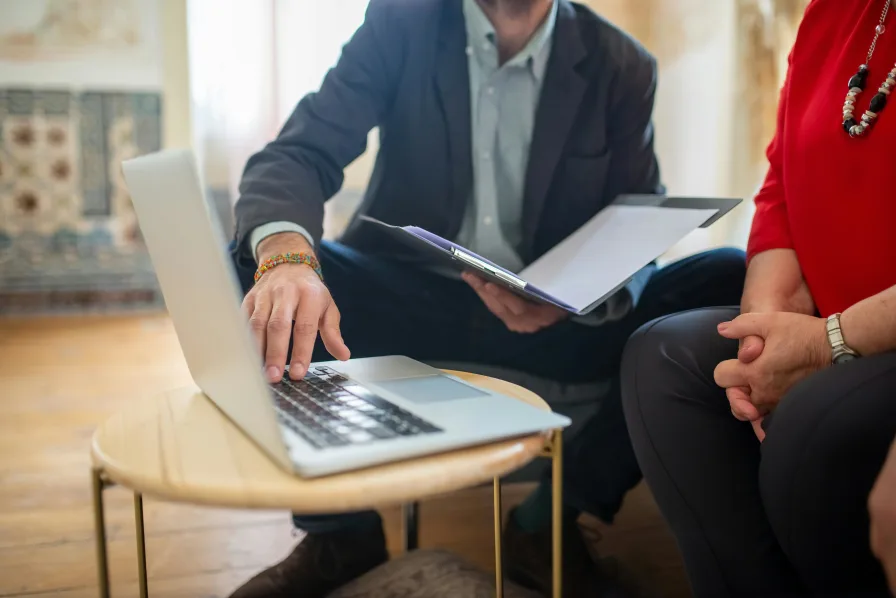 A real photo of a person meeting with an attorney at an office table, reviewing documents with a notepad and pen on the table, professional indoor lighting