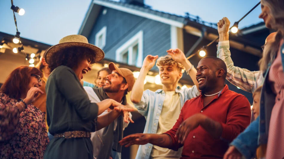 A small group of friends chatting in a backyard patio area with a dog nearby, realistic photography style