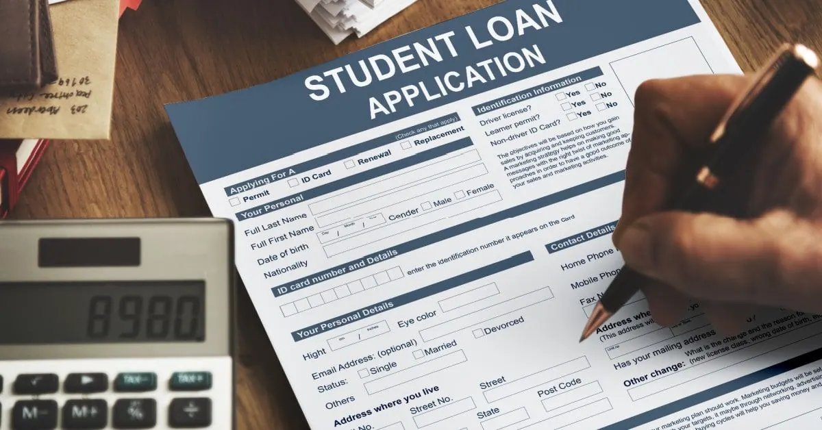 A stack of student loan paperwork next to a calculator and a pen on a kitchen table.