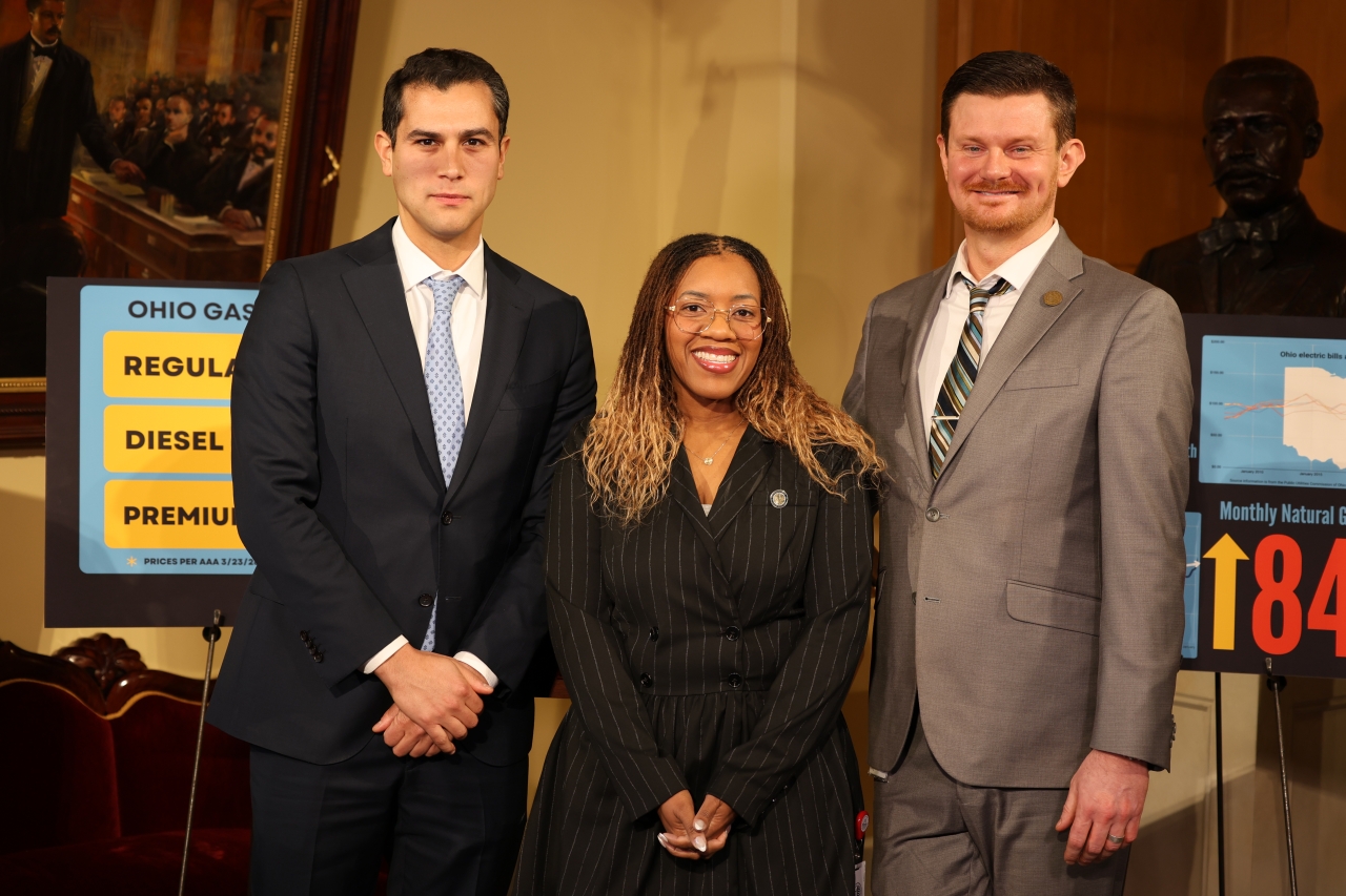 A stressed adult sitting at a kitchen table at night with open bills, a laptop, and a calculator, realistic indoor photograph