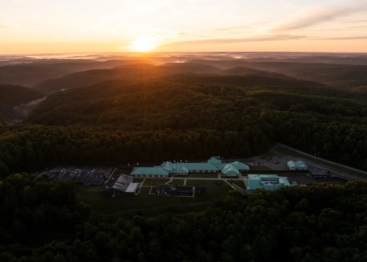 A teacher walking out of a public school building at sunset carrying a tote bag, realistic outdoor photography