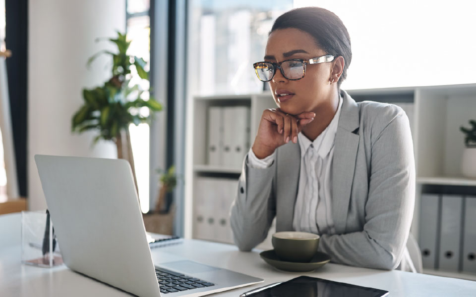 An employee sitting at a desk using a laptop to review workplace benefits options during open enrollment, office setting