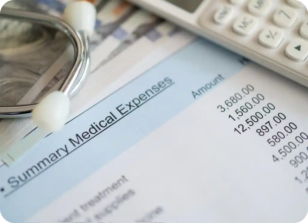 An older adult reviews medical bills and an insurance statement while using a calculator at a dining table.
