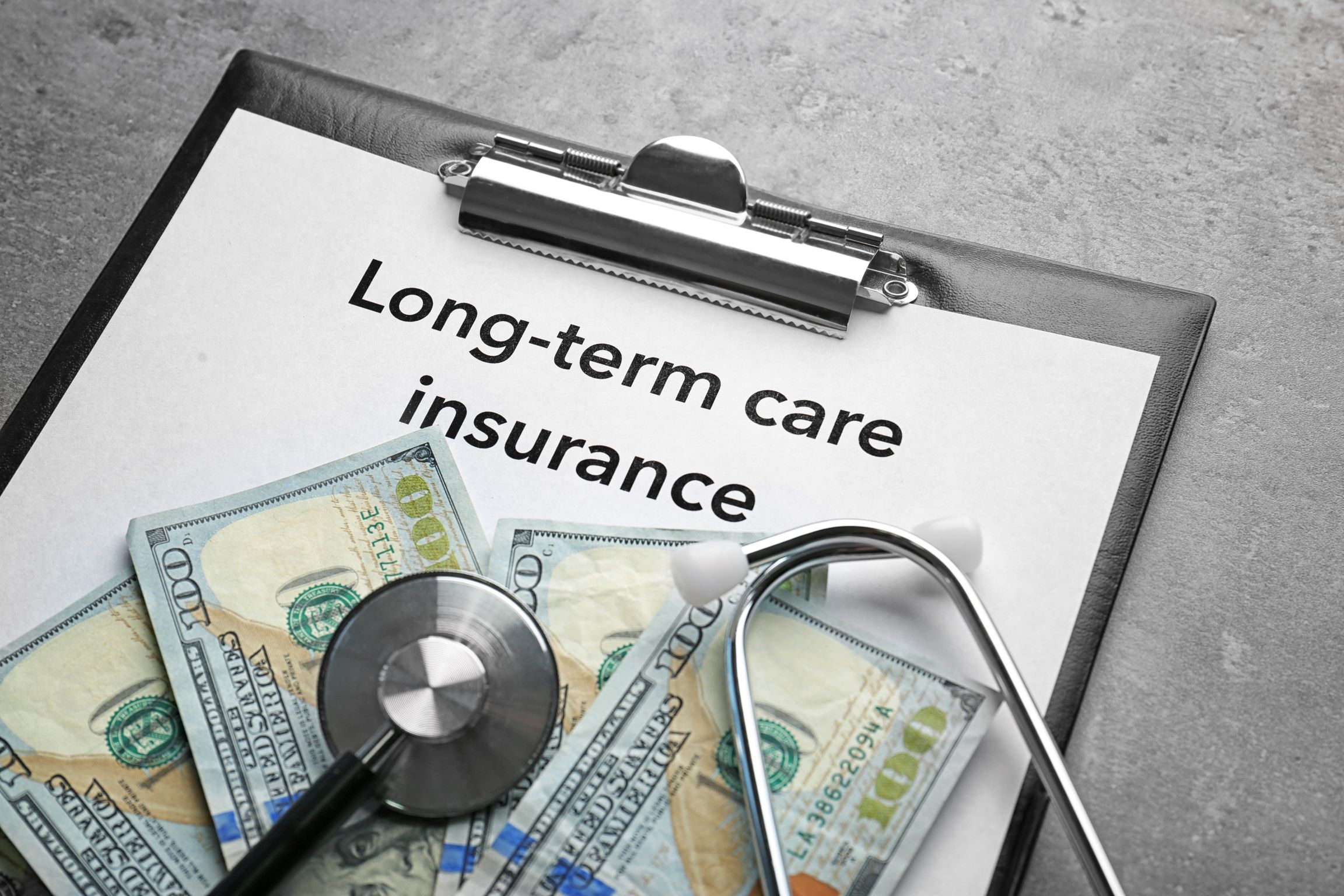 Long-term care insurance paperwork spread on a table with a pen and reading glasses nearby.