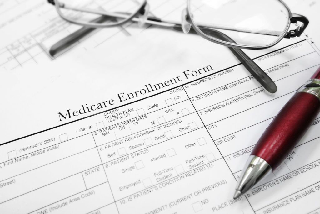 Medicare enrollment form on a kitchen table with a calculator and pen nearby.